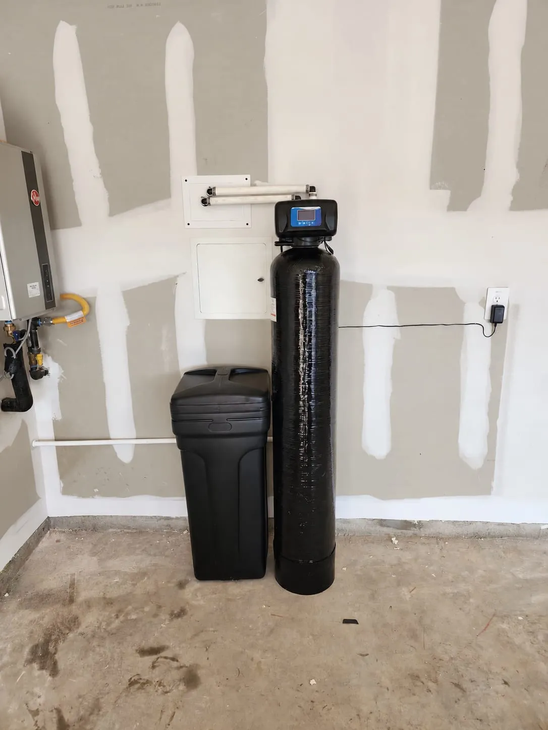 Water softener and carbon filter tank with brine tank installed in a garage next to a tankless water heater in Wilmington, DE