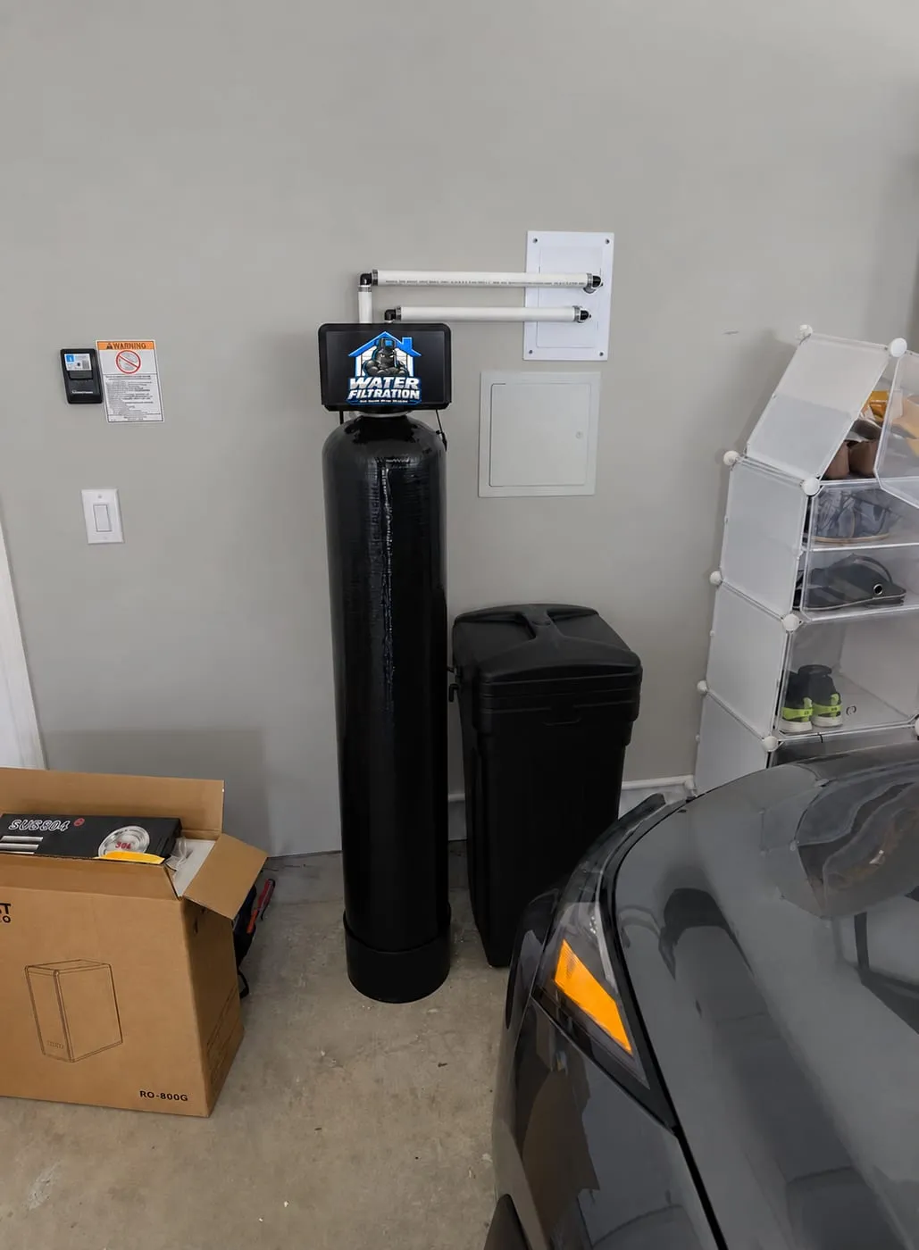 Whole-house filter and softener with the Water Filtration logo on the valve installed in a garage corner in Wilmington, DE