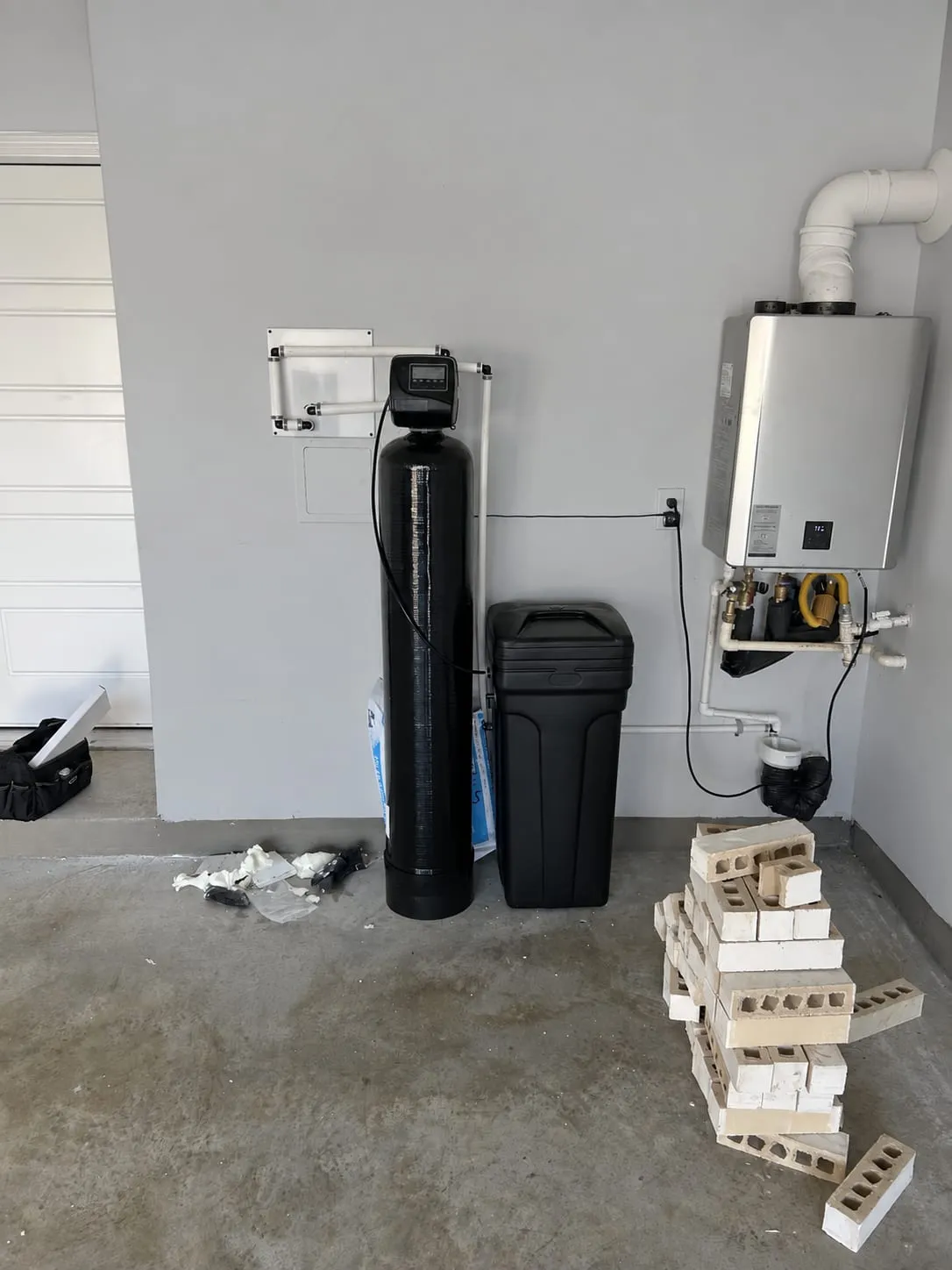 Water softener with brine tank and tidy plumbing installed next to a tankless water heater in Middletown, DE