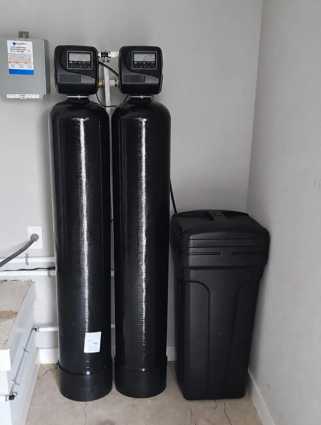 Dual-tank well water treatment system with brine tank installed beside a well pump control box in Dover, DE